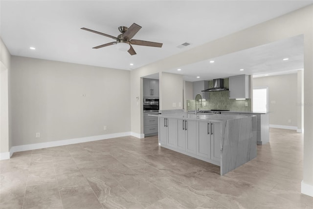 105 E Davis Blvd Unit A, Tampa, FL 33606 - kitchen featuring oven, an island with sink, gray cabinets, wall chimney exhaust hood, and a sink
