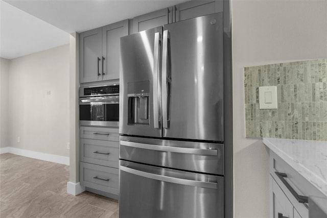 105 E Davis Blvd Unit A, Tampa, FL 33606 - kitchen with gray cabinetry, light stone counters, baseboards, and stainless steel appliances