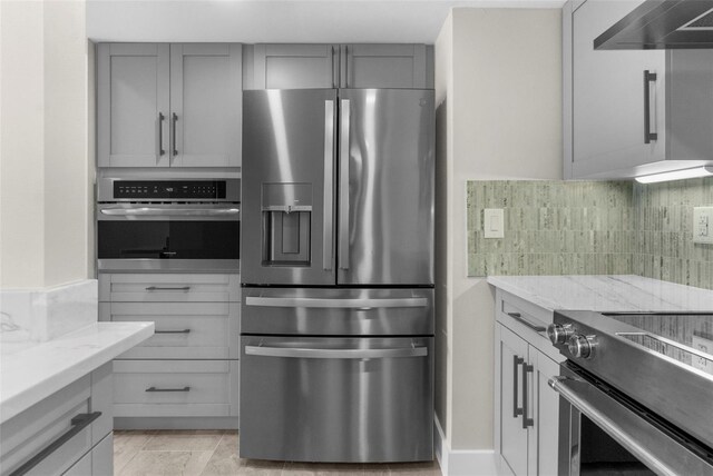 105 E Davis Blvd Unit A, Tampa, FL 33606 - kitchen featuring wall chimney range hood, stainless steel appliances, light stone countertops, and gray cabinets