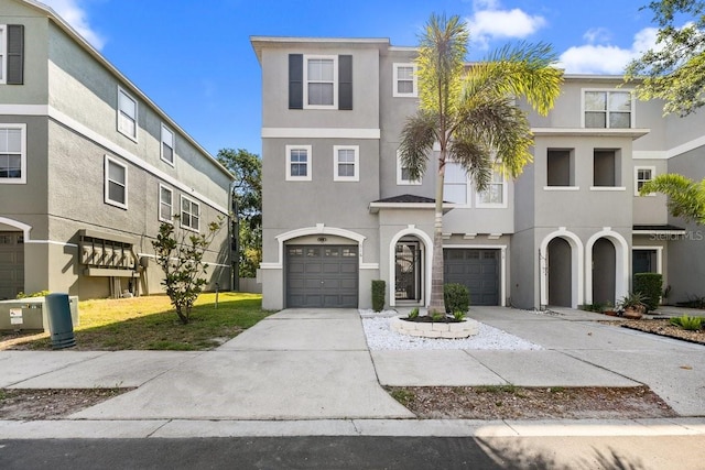 multi unit property featuring a garage, stucco siding, and driveway