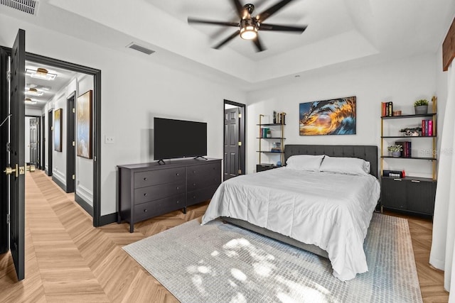 bedroom with a ceiling fan, baseboards, visible vents, and a raised ceiling