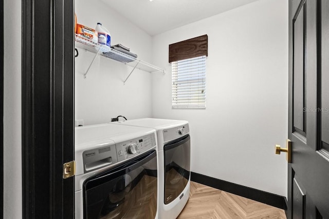washroom featuring separate washer and dryer, baseboards, and laundry area