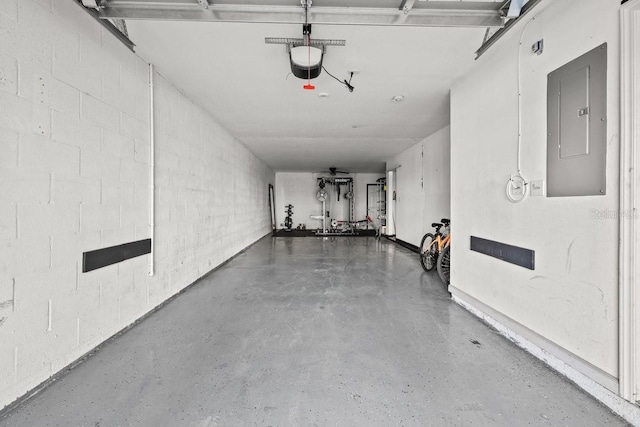 garage featuring concrete block wall, a garage door opener, and electric panel
