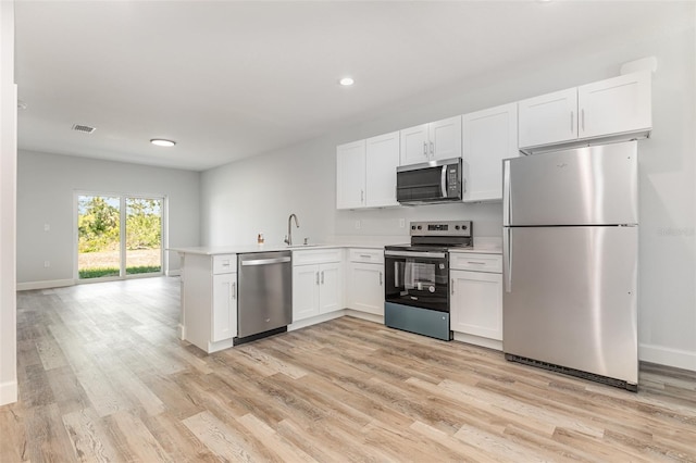 kitchen with visible vents, a peninsula, white cabinetry, light wood finished floors, and appliances with stainless steel finishes