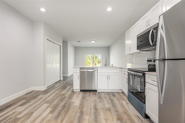 kitchen featuring light wood-type flooring, light countertops, white cabinetry, recessed lighting, and appliances with stainless steel finishes