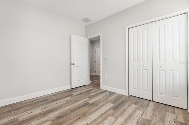 unfurnished bedroom with baseboards, a closet, light wood-style flooring, and visible vents