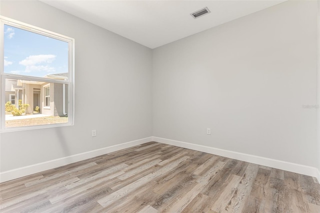 empty room with baseboards, visible vents, and wood finished floors