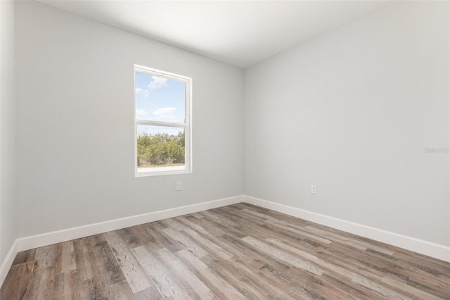 spare room with baseboards and wood finished floors
