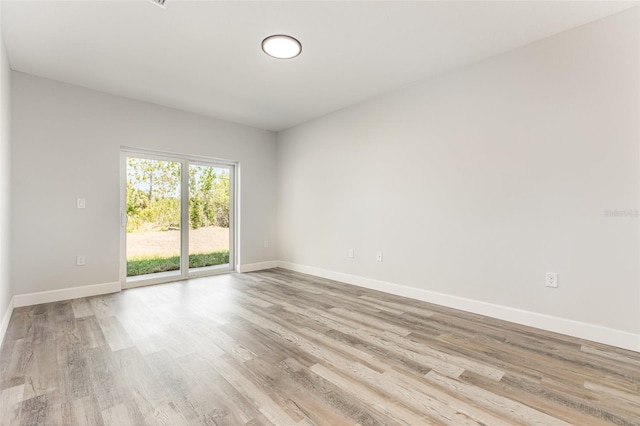 spare room with baseboards and light wood finished floors