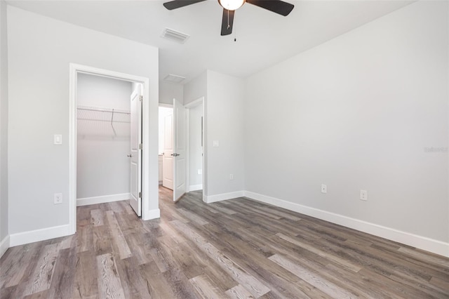 unfurnished bedroom with baseboards, a closet, wood finished floors, and visible vents