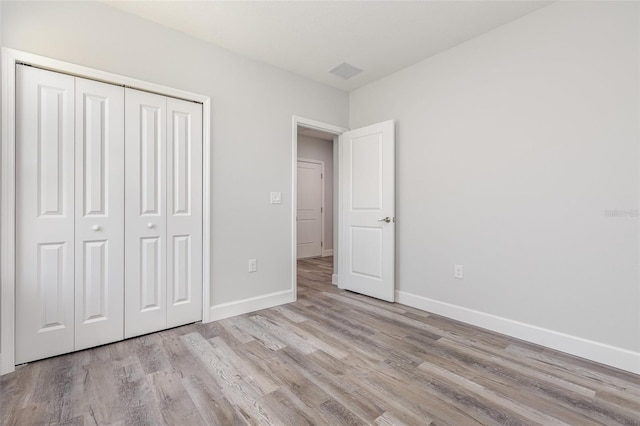 unfurnished bedroom featuring baseboards, visible vents, wood finished floors, and a closet