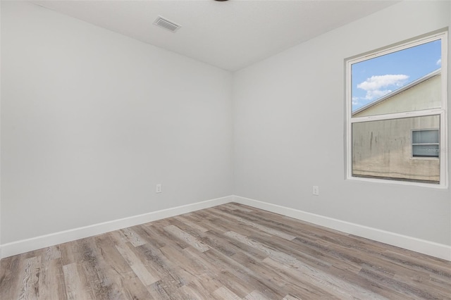 spare room featuring baseboards, wood finished floors, and visible vents