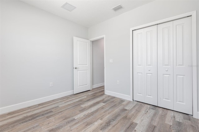 unfurnished bedroom featuring visible vents, baseboards, wood finished floors, and a closet