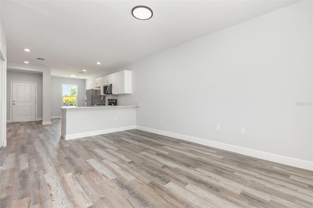 unfurnished living room featuring recessed lighting, baseboards, and light wood finished floors