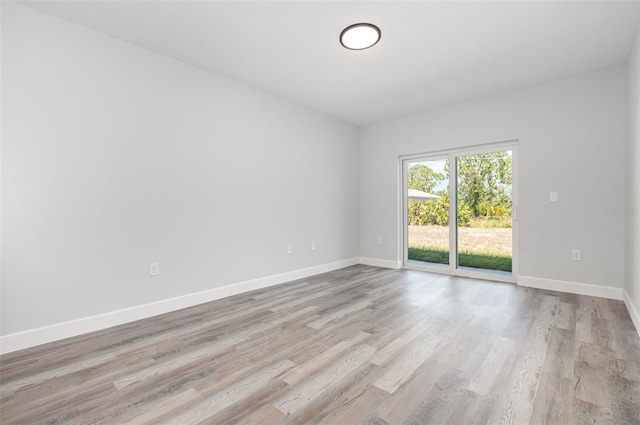 unfurnished room with light wood-type flooring and baseboards