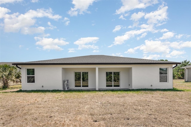 back of property featuring a lawn and stucco siding