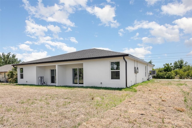 rear view of property featuring a yard and stucco siding
