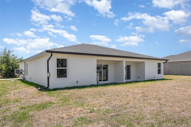 back of property featuring a lawn and stucco siding