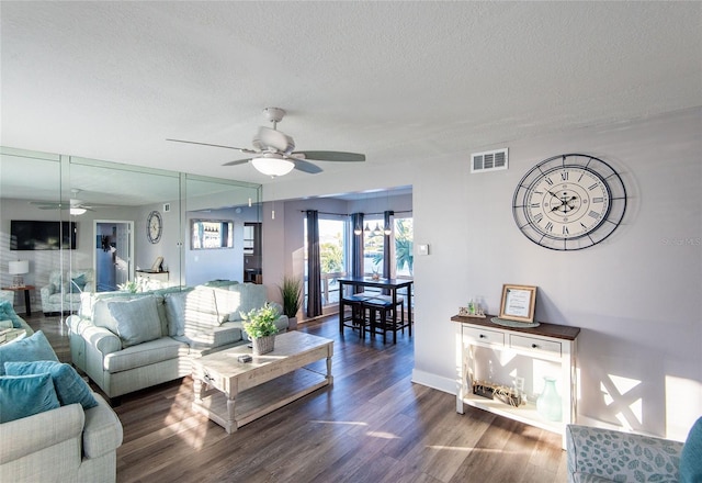 living area featuring a textured ceiling, a ceiling fan, wood finished floors, and visible vents