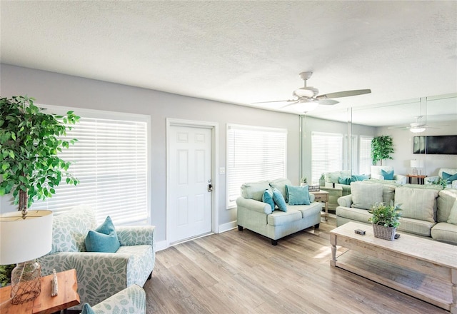 living area with a ceiling fan, light wood finished floors, and a textured ceiling