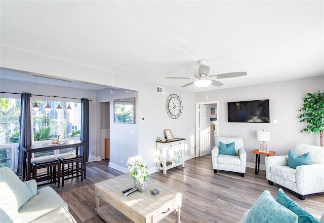 living room with a ceiling fan, baseboards, visible vents, and wood finished floors