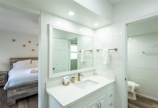 bathroom with vanity, toilet, wood finished floors, and ensuite bath