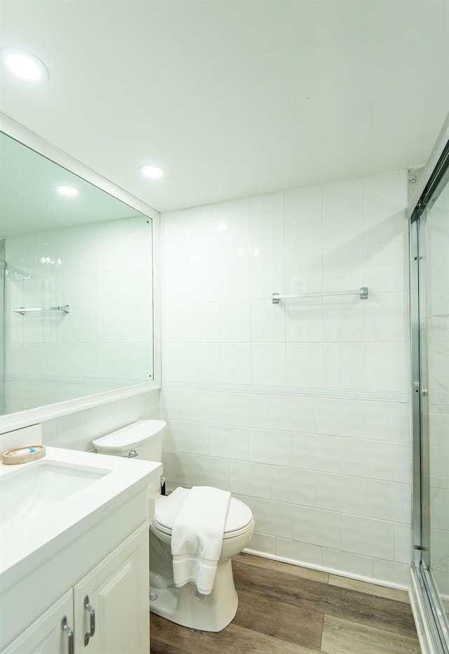 bathroom featuring a stall shower, wood finished floors, vanity, toilet, and recessed lighting