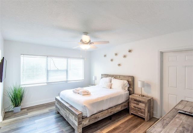 bedroom featuring a textured ceiling, ceiling fan, baseboards, and wood finished floors