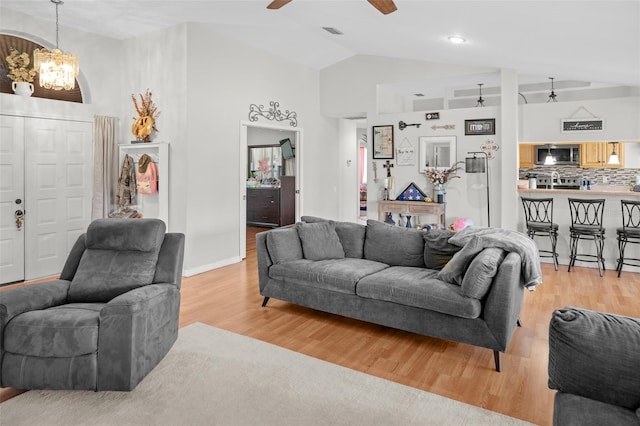 8712 Ashbury Dr, Hudson, FL 34667 - living area featuring high vaulted ceiling, ceiling fan with notable chandelier, light wood-style flooring, and visible vents