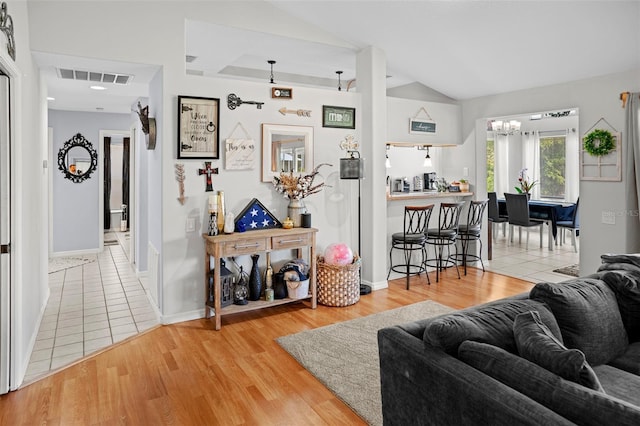 8712 Ashbury Dr, Hudson, FL 34667 - living area with visible vents, vaulted ceiling, baseboards, light wood finished floors, and a notable chandelier