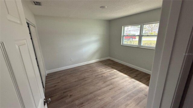 3188 Lake Saxon Dr, Land O Lakes, FL 34639 - unfurnished bedroom featuring a textured ceiling, baseboards, wood finished floors, and visible vents