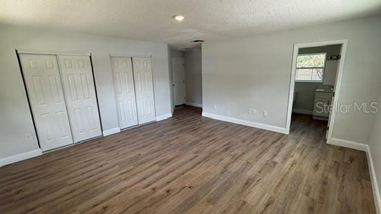 3188 Lake Saxon Dr, Land O Lakes, FL 34639 - unfurnished bedroom featuring baseboards, a textured ceiling, multiple closets, and wood finished floors