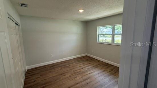 3188 Lake Saxon Dr, Land O Lakes, FL 34639 - unfurnished bedroom featuring visible vents, a closet, wood finished floors, baseboards, and a textured ceiling