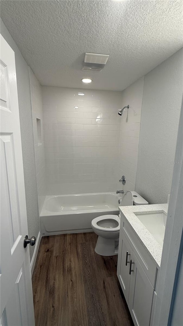 3188 Lake Saxon Dr, Land O Lakes, FL 34639 - bathroom featuring a textured ceiling, wood finished floors, vanity, toilet, and washtub / shower combination