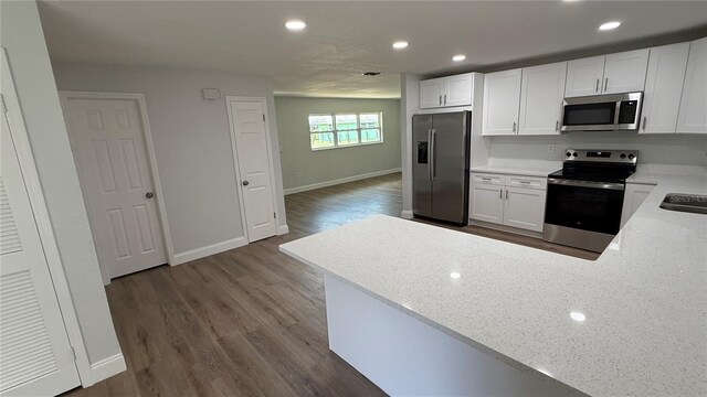 3188 Lake Saxon Dr, Land O Lakes, FL 34639 - kitchen featuring white cabinets, dark wood-style flooring, appliances with stainless steel finishes, recessed lighting, and baseboards