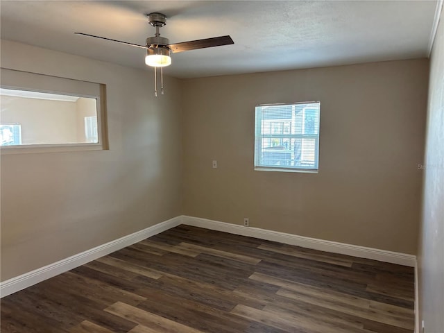 spare room featuring baseboards, ceiling fan, and dark wood-type flooring