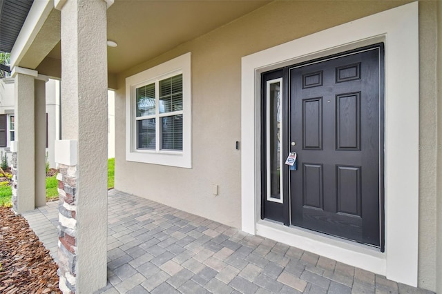 doorway to property with stucco siding and covered porch