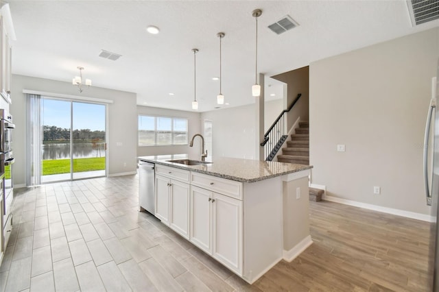 kitchen featuring visible vents, light wood-type flooring, a sink, and dishwasher