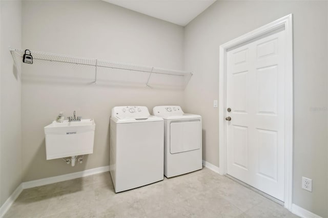 laundry area with a sink, separate washer and dryer, baseboards, and laundry area