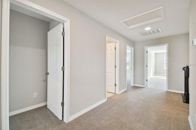 corridor with carpet floors, baseboards, visible vents, and attic access