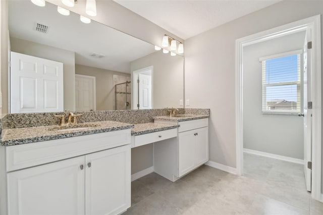 bathroom with a sink, a shower stall, double vanity, and visible vents