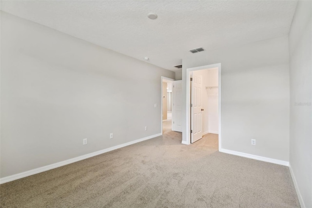 unfurnished bedroom featuring a walk in closet, carpet floors, baseboards, visible vents, and a closet