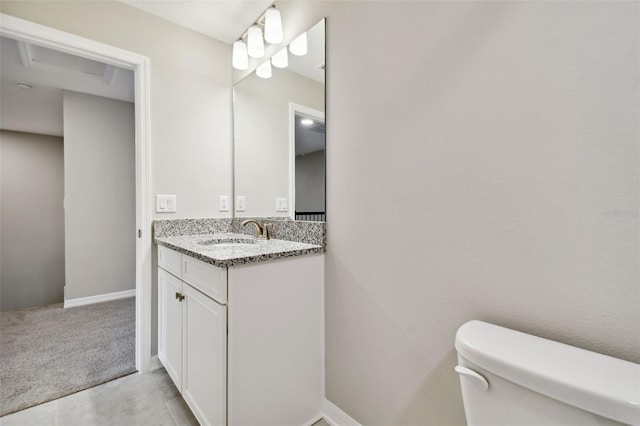 half bath with toilet, baseboards, and vanity