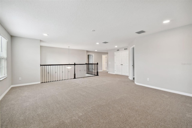 carpeted spare room with visible vents, recessed lighting, baseboards, and a textured ceiling