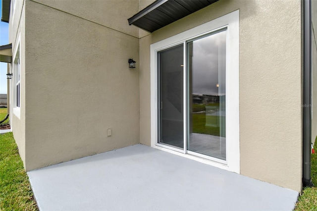 property entrance featuring stucco siding and a patio area