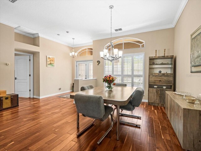 dining space featuring dark wood-style flooring, visible vents, baseboards, a chandelier, and ornamental molding