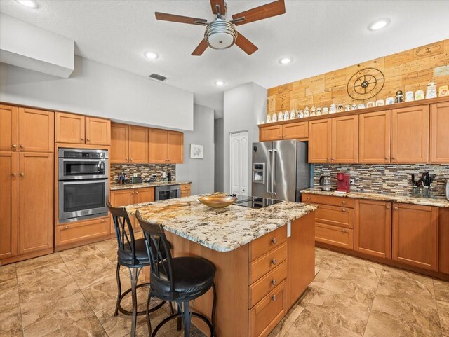 kitchen with appliances with stainless steel finishes, a center island, a ceiling fan, wine cooler, and visible vents