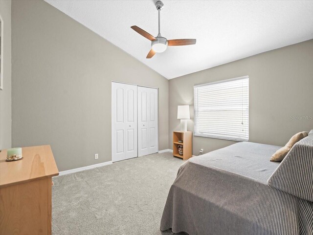 carpeted bedroom with a closet, baseboards, ceiling fan, and vaulted ceiling