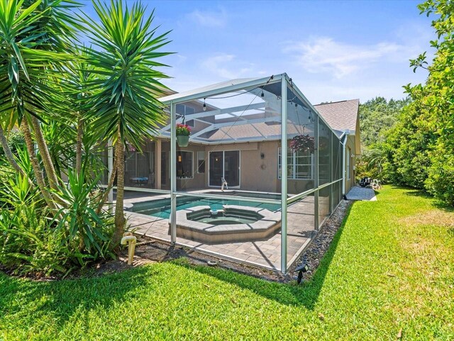 back of house featuring an outdoor pool, an in ground hot tub, a patio, a yard, and glass enclosure
