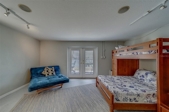 620 Bayway Blvd Unit 1, Clearwater, FL 33767 - bedroom with french doors, a textured ceiling, track lighting, baseboards, and access to outside